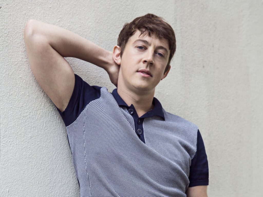 Alex Sharp as Rennie Davis